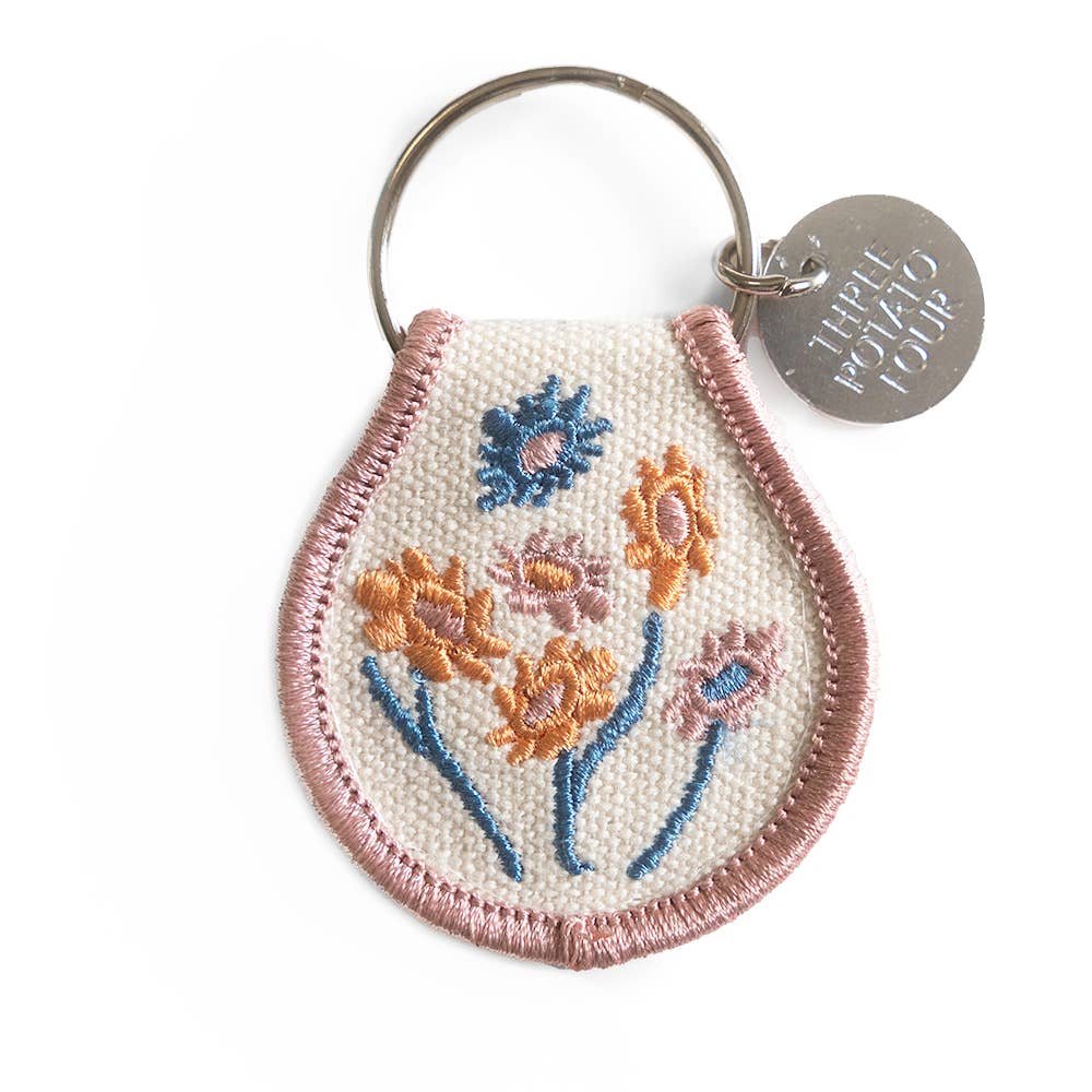 Embroidered floral keychain with a 'Three Potato Four' tag on a white background
