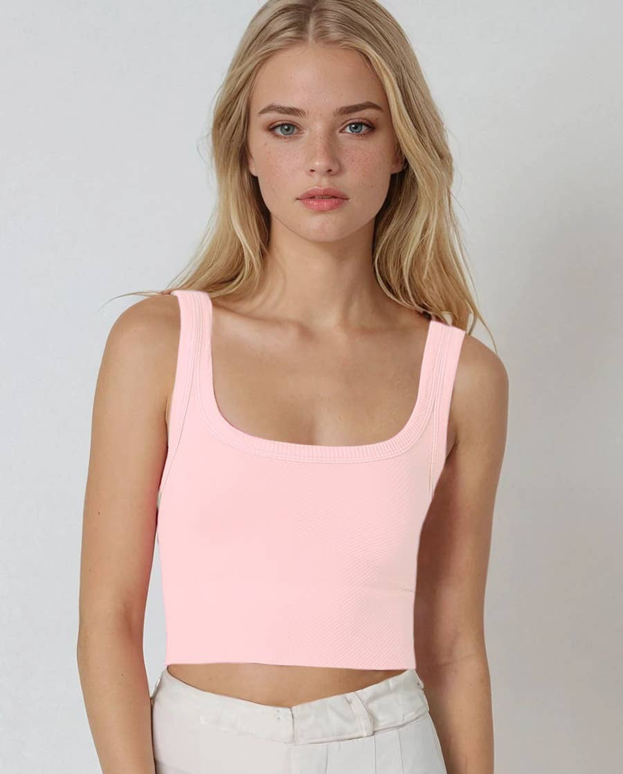 Woman wearing a light pink tank top against a plain background