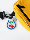 Yellow bag with a keychain featuring cherries on a white background