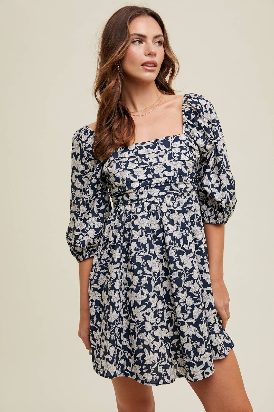 Woman wearing a floral dress against a beige background