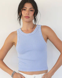 Woman wearing a light blue ribbed tank top against a white background
