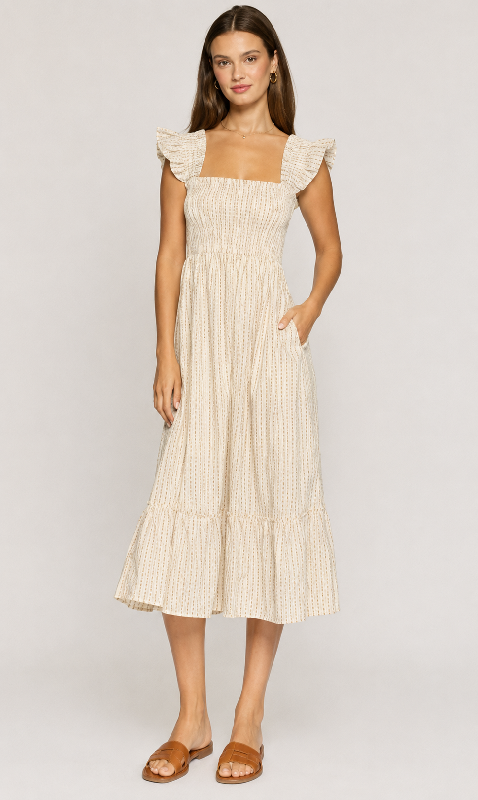 Woman wearing a beige dress with ruffled sleeves on a white background