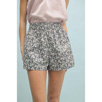 Person wearing floral shorts and a pink top on a light blue background
