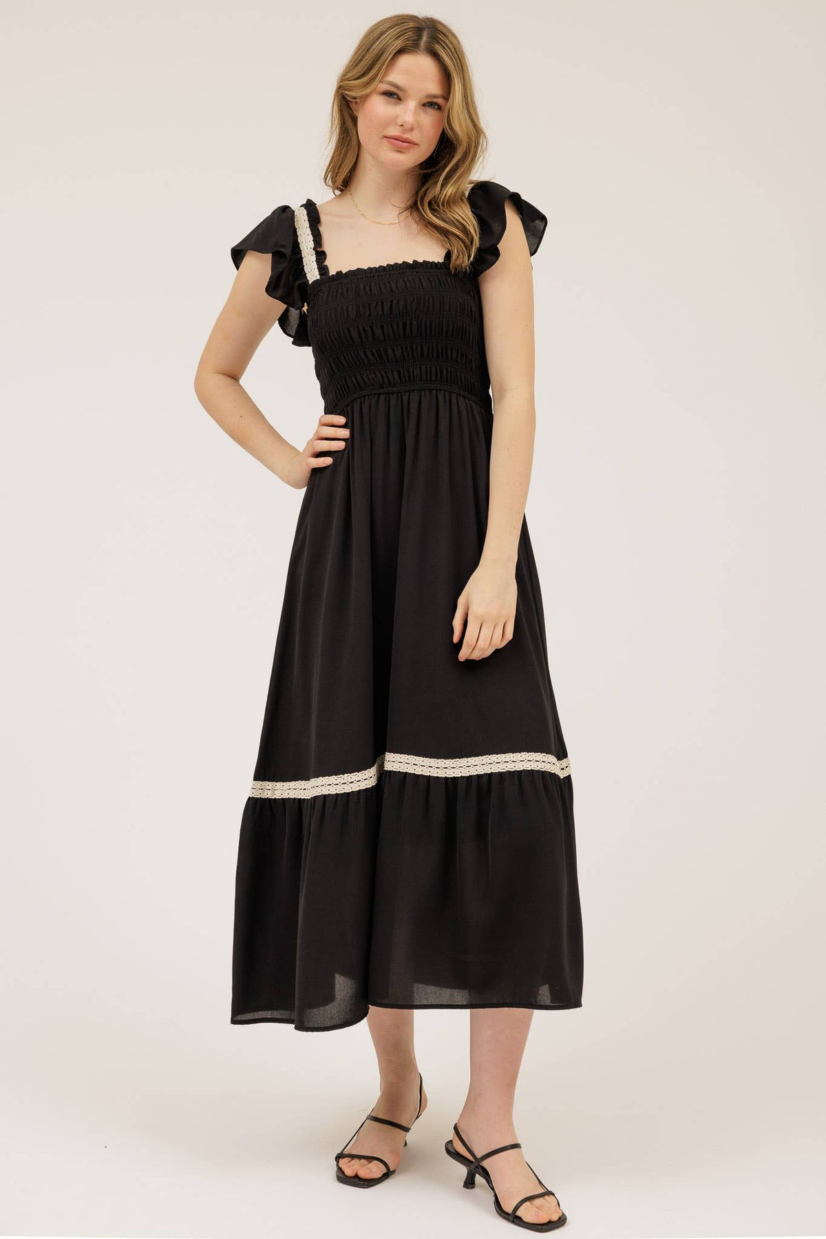 Woman wearing a black dress with white trim on a white background